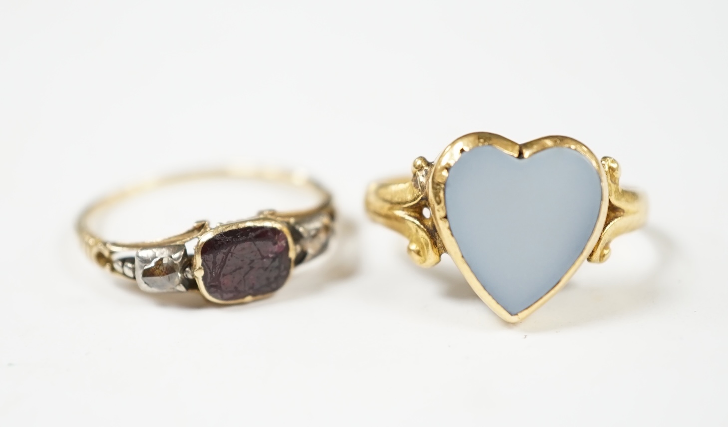 A Victorian yellow metal, garnet and rose cut diamond set three stone ring, size N/O, together with a later yellow metal and white chalcedony set heart shaped ring, gross weight 5.8 grams. Condition - poor
